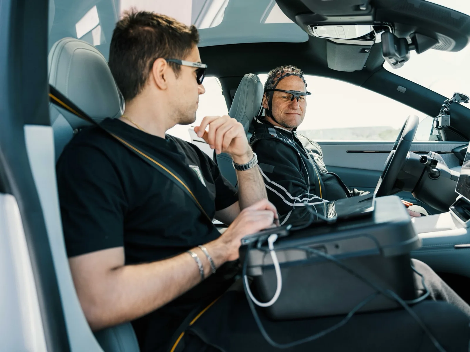Onderzoeker met laptop naast een bestuurder met meetkap en oogmeetbril in een Polestar 4