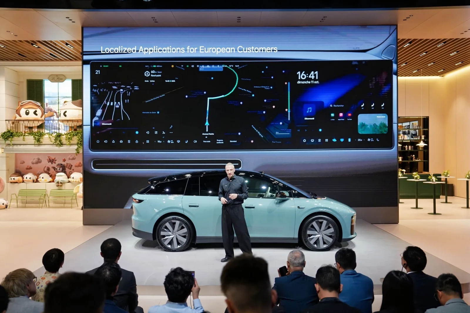 Presentator naast een mintgroene Li Auto Li 6 met zwart dak op de autosalon van Parijs