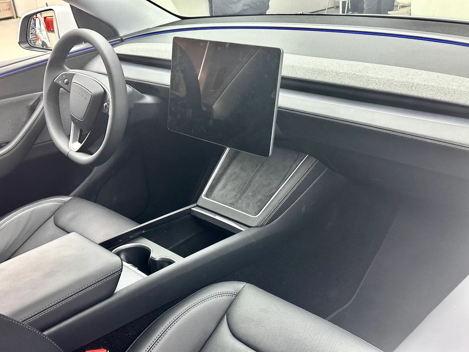 Interieur van een vernieuwde Tesla Model Y met zwarte stoelen en een groot middenscherm