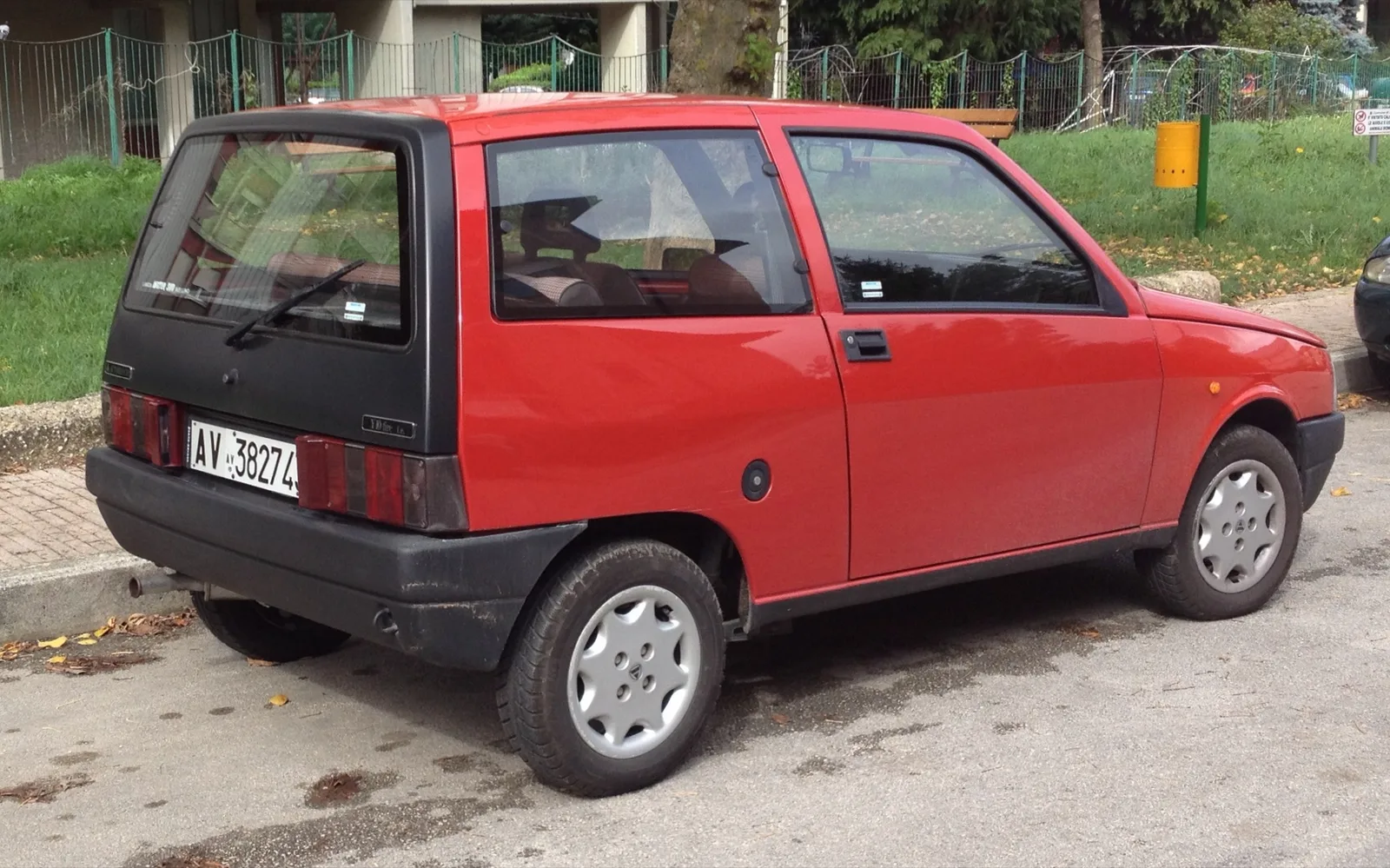 Rode Autobianchi Y10 van schuin achteren met zwarte achterklep