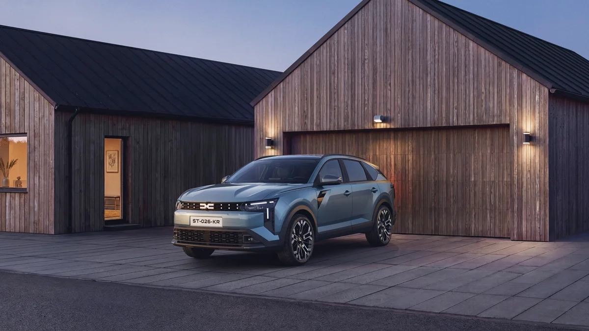 Groene Dacia Striker van schuin voren, geparkeerd voor houten huizen in de schemering