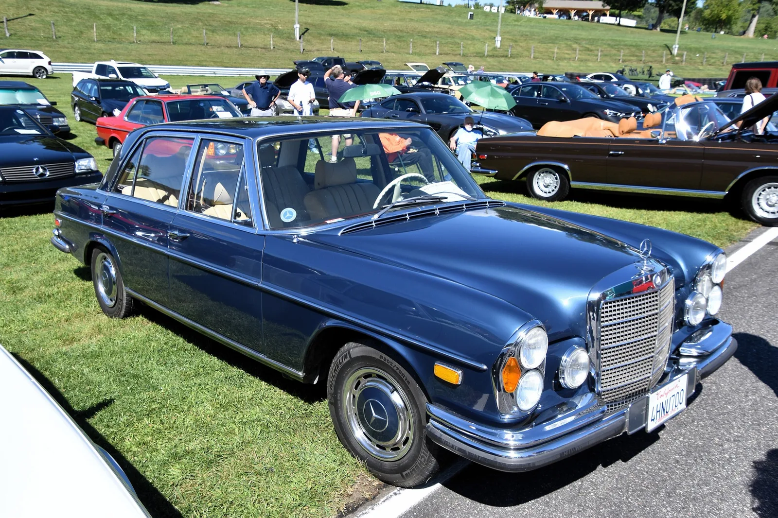 Blauwe Mercedes-Benz 300 SEL 6.3 uit 1969 van schuin voren op een grasveld